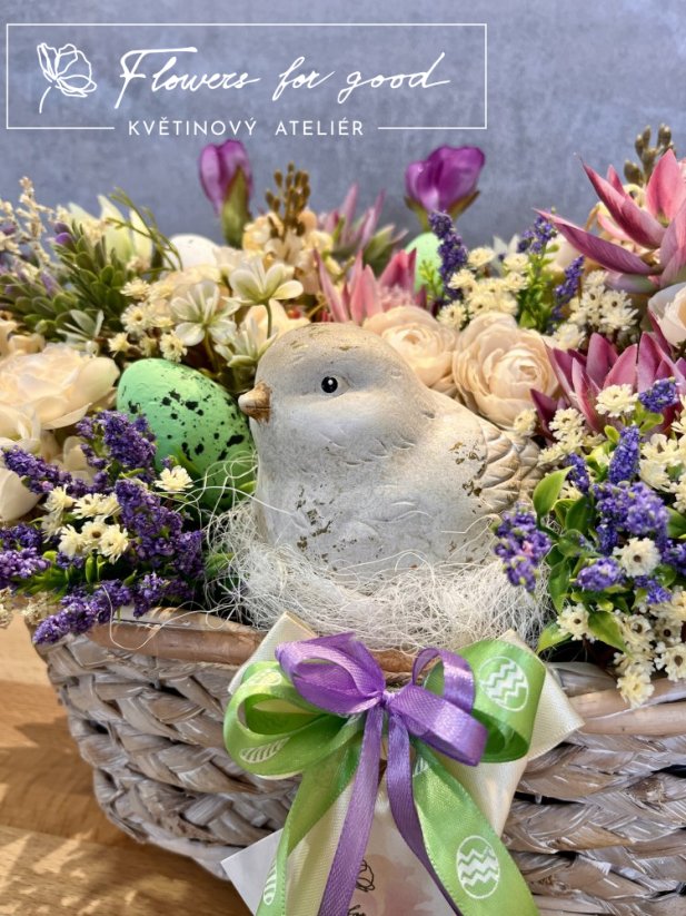 Velikonoční ošatka s ptáčkem v hnízdě mezi květinami