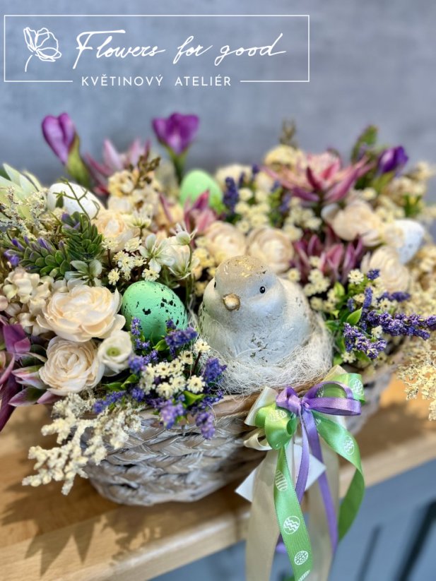 Velikonoční ošatka s ptáčkem v hnízdě mezi květinami